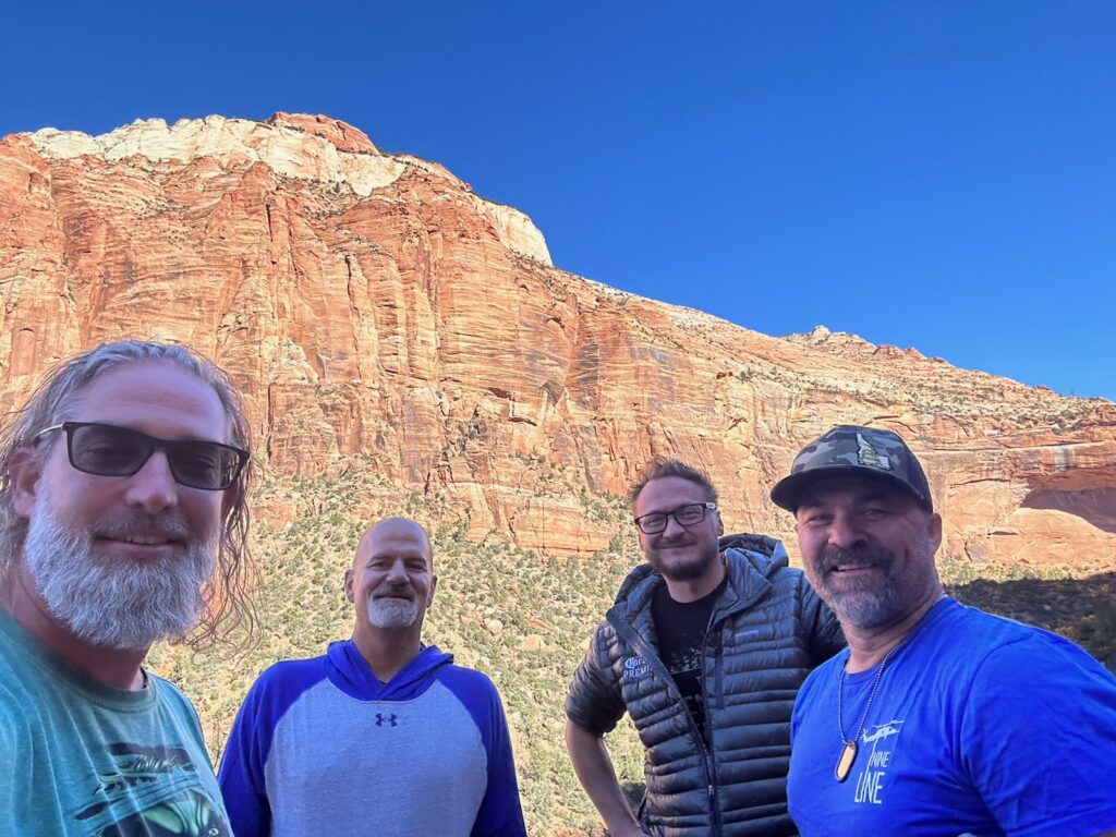 A group of men standing in front of a mountain.